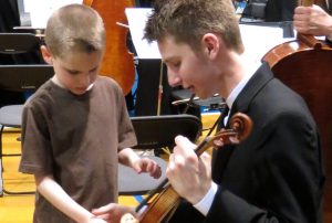  Senior Nick Alm lets a Kansas State School for the Blind student touch a violin after a performance while on tour to Kansas City on April 10-13.