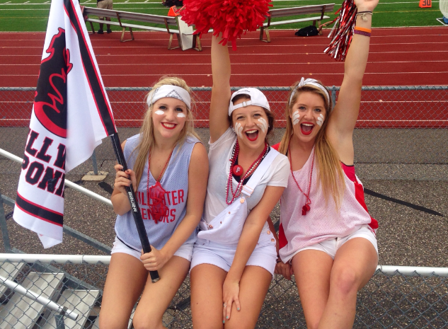 Senior Superfans Grace Charpentier, Megan Aller and Erin Theits dress in all white for the whiteout against Roseville in the first game of the Ponies 2014 season. Grace holds the flag that excites Pony Pride when its waved. They are always so energetic! said junior Ella Janochoski, it motivates us all to go to the games!
