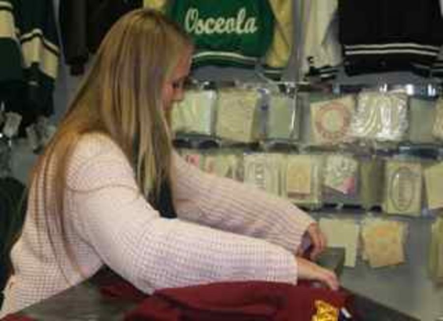 
 Junior Mikaela Fritsche folds a sweatshirt at Heritage Embroidery, a local retail clothing store. Many high school age students work at Heritage, including seniors Maddy Boettner and Jenny Hammer. Clothing is one of the most well known retail items, which is the main focus of Heritage, along with some decals and embroidering.