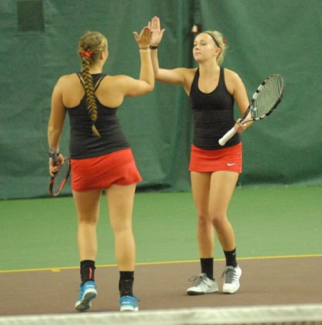 Seniors Shelby Anderson and Savannah Johnson hive-five each other after the end of a volley during their match against Duluth East in the consolation tournament. "It was incredible to look up in the stands and see all our friends and family cheering us on." senior Shelby Anderson said.