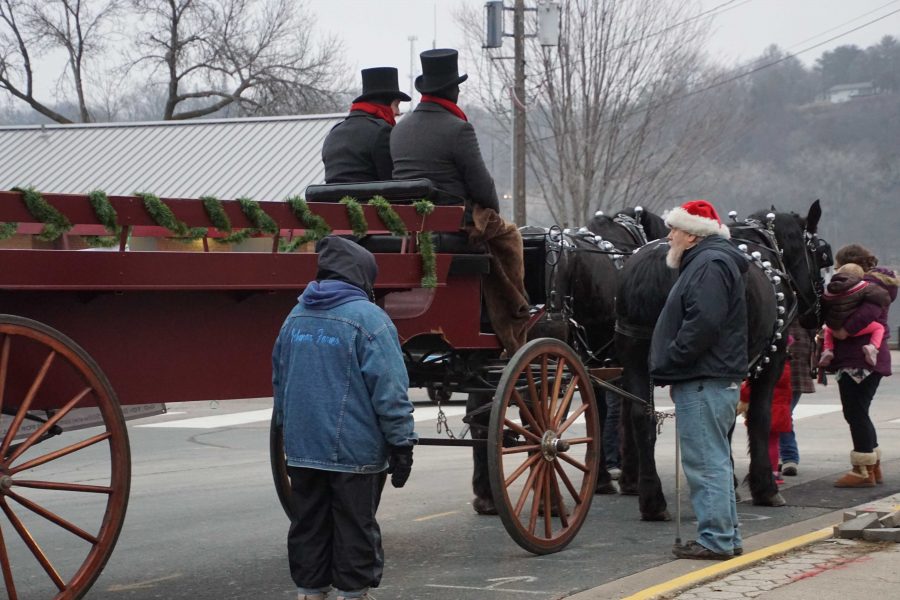 Santa stands near his horses and carriage waiting for the next group to ride. Anyone from couples to families were welcome aboard. After each ride he asked, Alright folks did you have fun? and everyone replied Yes.