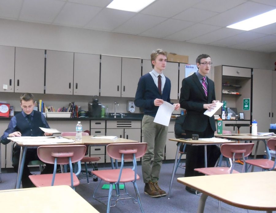 Debates take place in a classroom setting, with each team side-by-side and a desk in the middle if a podium was unavailable. On the other side of the room, a single judge sits for rounds 1 through 4, while three judges gage the final rounds. “When you’re in a debate round, your mind more focuses on what is going on in a debate, rather than who’s watching,” senior and captain Jack Franz (middle) says. Senior Justin Hannasch (on the left and also a captain) works on finding holes for potential retaliation during a round of cross-examination while his partner, Franz answers to the opponent (right). 
