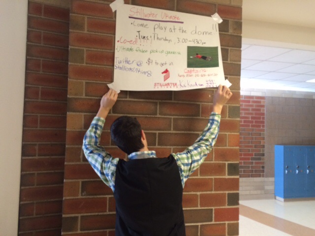 Noah Linder places a poster up on a wall at school. Now that the ultimate team is an activity they are allowed to advertise themselves at school. This allows them to recruit more members.