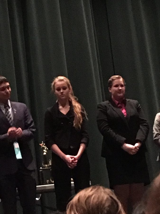 Sophomore Lauren Capra (center) waits to receive her first place award after giving her speech.  The year started out well with a first place win by Lauren Capra in the category of informative, speech team coach, Laura Hammond says.