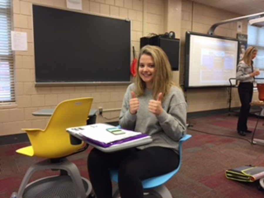 This is Katie F sitting in the newspaper room, giving a double thumbs up because she is happy to be here.