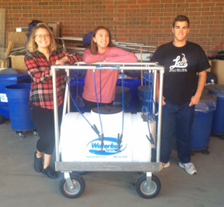 Photo By Thomas Johnson - Pictured from left to right are senior managers Megan Felsch, Sydney Slusher, and Josh Stivland. Getting ready for practice as they wheel the water out. Megan explains, We are in charge of getting the water boy full of water at all times, so the players always have water.