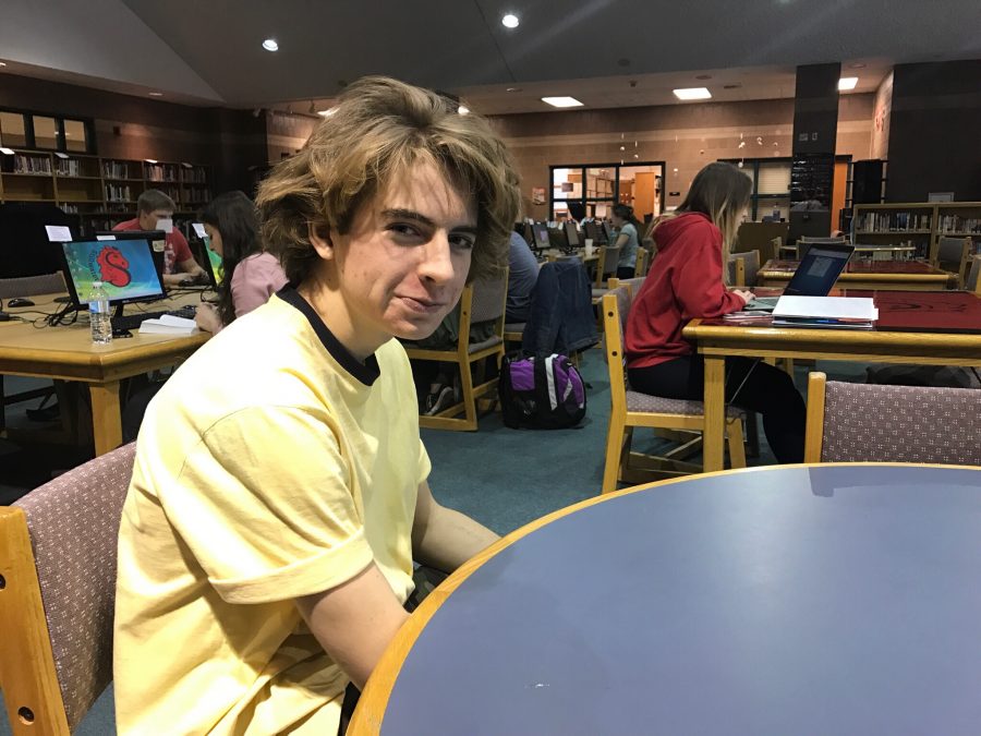 A photo of Dylan Cook in the school library. Cook is a photographer, and has won an gold key award, and is competing in the Scholastic Arts Competition. Cooks photographs are in an exhibit in Washington DC.