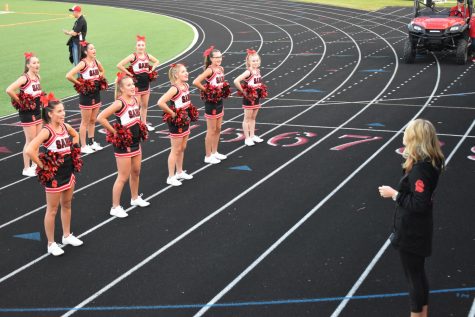 Julie Ligday walks the new cheerleading squad through a cheer at the first game of the season