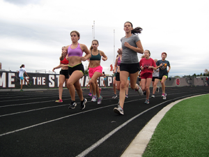 Girls cross country runners turn the corner on the track at practice.  
