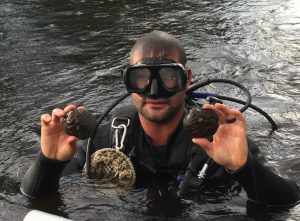 A man from the DNR attended a trip to the St. Croix with Chaplinksi and her students. He holds an endangered Winged Mapleleaf Mussel in each hand.