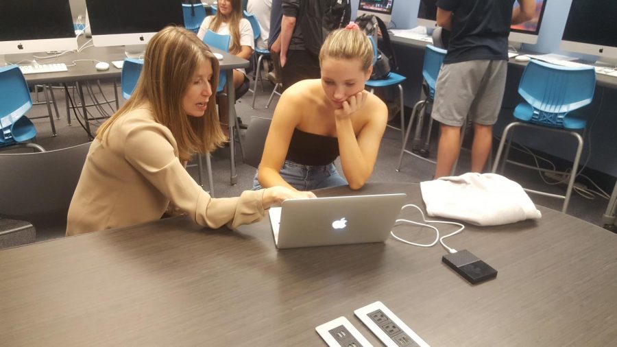 Teacher Deb Drew and senior Lola Wallace working on a client video.