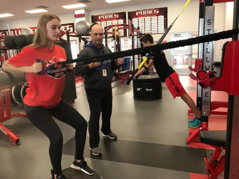 Salmi helping sophomores Sarah Hanselman and Ethan Vargas work out during physical education class.