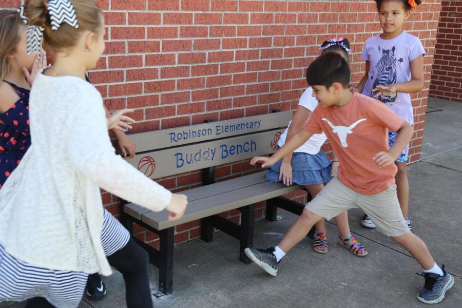 The kids are using the Buddy Benches at Anderson Elementary School. The kids use the benches to find new friends.