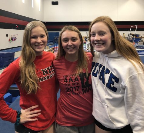 Gretchen Sharp, Isabel Bartosh and Peyton Classon smiling in their home gym. Before practice, the gymnasts show their excitement. 