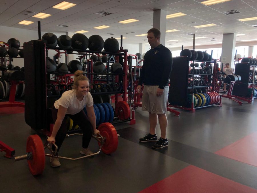 Chad Bischoff guides freshmen Caroline Monty through an exercise. Chad is just an all around great guy, he wants to help you get stronger so hes always there to make sure you are doing the workouts right, junior AJ Schoenecker says.
