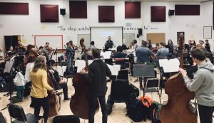 Concert orchestra works through a musical piece while be lead by director Zach Sawyer. The group leaves for Boston March 28. 