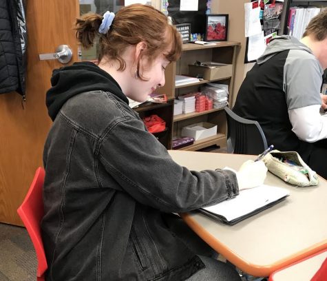 Junior Grace Wirrkala sits in class on March 20. She is wearing 80s and 90s fashion trends with her jean jacket and blue scrunchie.