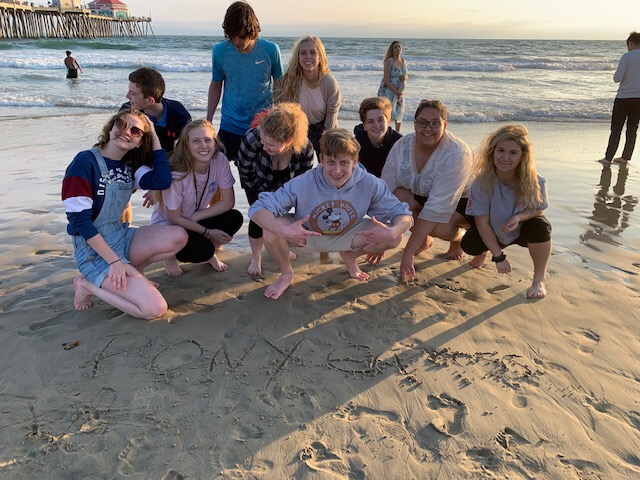 Go go go! After numerous attempts, Pony Express students finally beat the tide and pose with their newspaper title written in the sand.