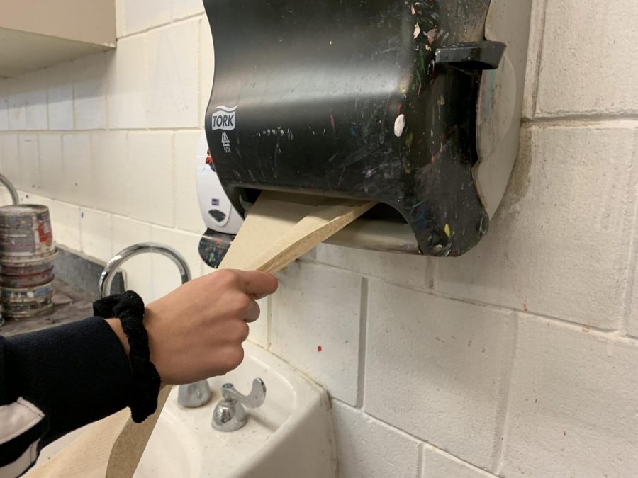 Senior Emma Boehle grabs a handful of paper towels for her class sculpture. Clay classes use handfuls of towels everyday to cover their projects, contributing a large chunk to the overall paper towel waste. This is one area the school can look to reduce waste.