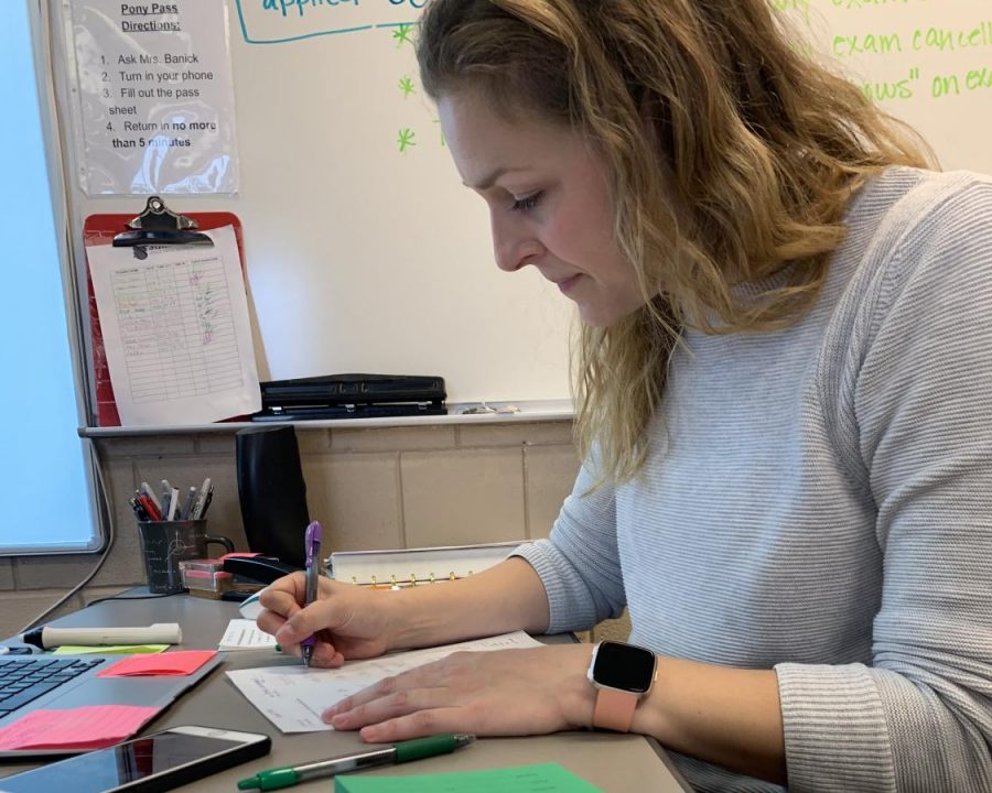 Math teacher Amanda Banick sits at her desk grading homework from previous class periods. She is using the new policy of the 20 percent formative and 80 percent summative to correct the students review sheets.