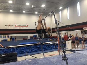 Junior Heather Wiehe practices for the season by working on her up rises on the uneven bars in the gymnastics gym. Coach Dusty Dennis prepares with gymnasts for the upcoming season.