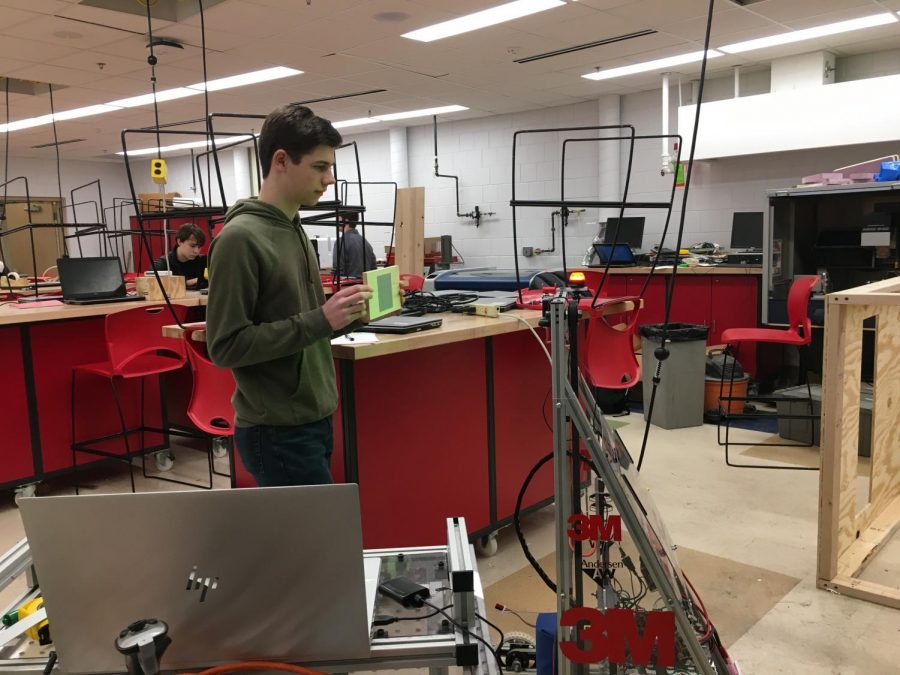 Robotics captain junior Ben Abbott is testing the robots programming to make adjustments. The robot can sense the light that reflects back at the sensors from the reflective tape.