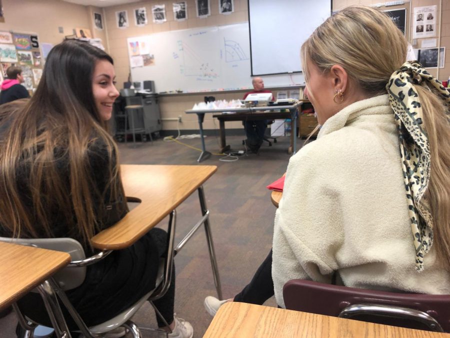 Engaging in conversation during Journalism class, seniors Alayna Christian and Sophie Watkins discuss the different stereotypes associated with high school girls on Feb. 11.