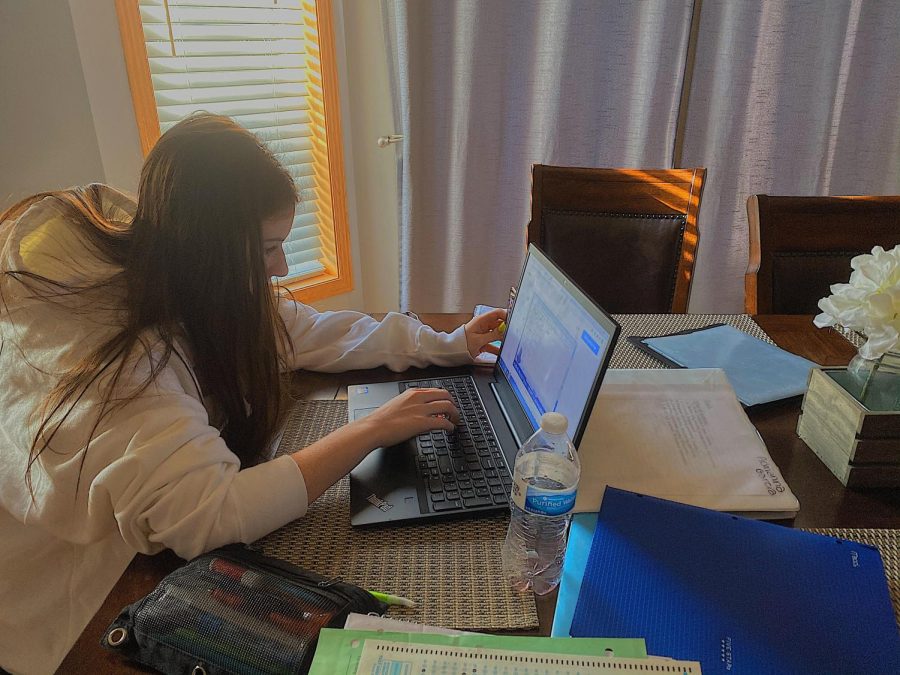 Grade 9 SAHS student Alicia Garcia works on her schoolwork at home. She has many documents surrounding her in order to productively work.