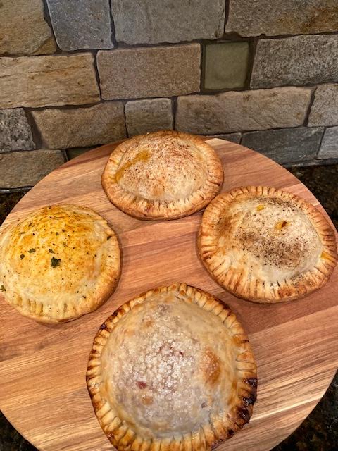 Four sweet and savory pastry pockets are set on a table. Each one is later tried and reviewed for the food blog. 

