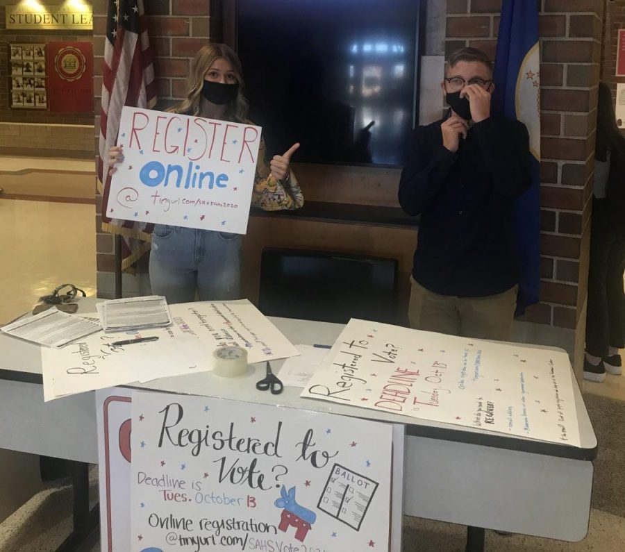 Seniors Alex Steil and Natalie Loehr try to bring in students to their voting booth. On Oct. 12 and 13, the Young Democrats and Young Republicans ran a booth in the main rotunda to register seniors that are eligible to vote.