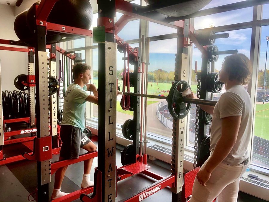 Seniors Nick Cherry and Flynn Opstad sanitize a barbell in the weight room after a workout with the football team. Keeping the weights clean is a key factor in limiting contact between players and other students using the gym.