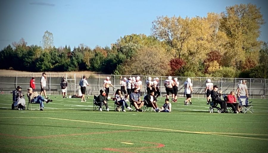 Captured in this photo is the varsity football team practicing for their game against White Bear on Oct. 9. They are practicing on one of the many practice fields, located in the back of the school. As seen in the photo, the coaches have masks or face coverings on, along with some of the parents and family members watching the practice.