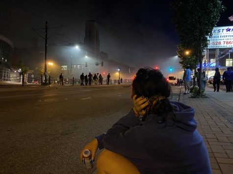 Senior Missa Lunzer watches the protests from a distance. She sits on the side of the street to recover from being tear gassed. The streets are full of smoke yet people stay out to chant. 