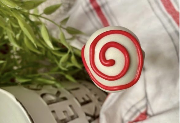 This image is of a cake pop from the top view with the design of a swirl made from the frosting.  
