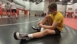 Sophomore Zach Hunter gets ready for wrestling practice while wearing a mask due to Governor Walz mask mandate.