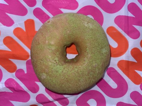 This image shows an overhead picture of the new Dunkin Matcha Topped Donut.  The vibrant green and exotic flavor makes people curious and eager to give this donut a try. 
