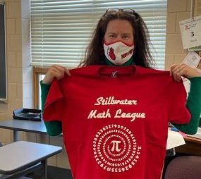 Stephanie Nord, the advisor for the stillwater math league, holds up a team T-shirt in the classroom where they normally meet. Due to COVID-19 the team did not print out new shirts for the 2020-21 season.
