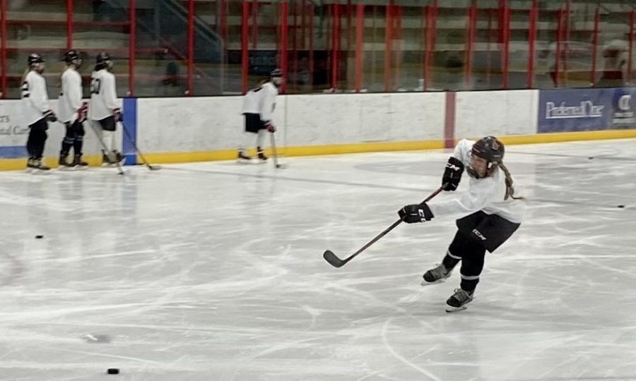 Number 49 shoots puck on goal during practice. Girls hockey team is putting their all in getting ready for hockey season.