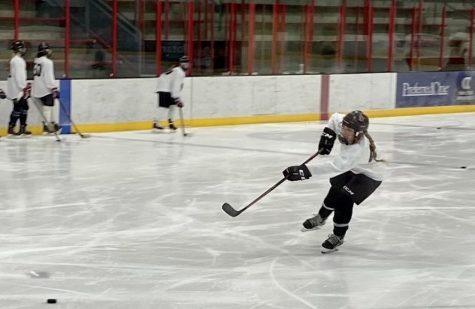 Number 49 shoots puck on goal during practice. Girls hockey team is putting their all in getting ready for hockey season.
