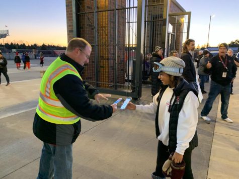 Senior Sophia Heidke scans her ticket with a ticketing worker to enter the varsity football game.