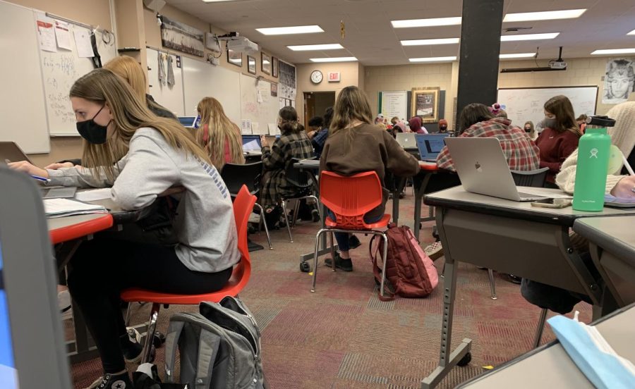 Students work on computers in a crowded classroom.