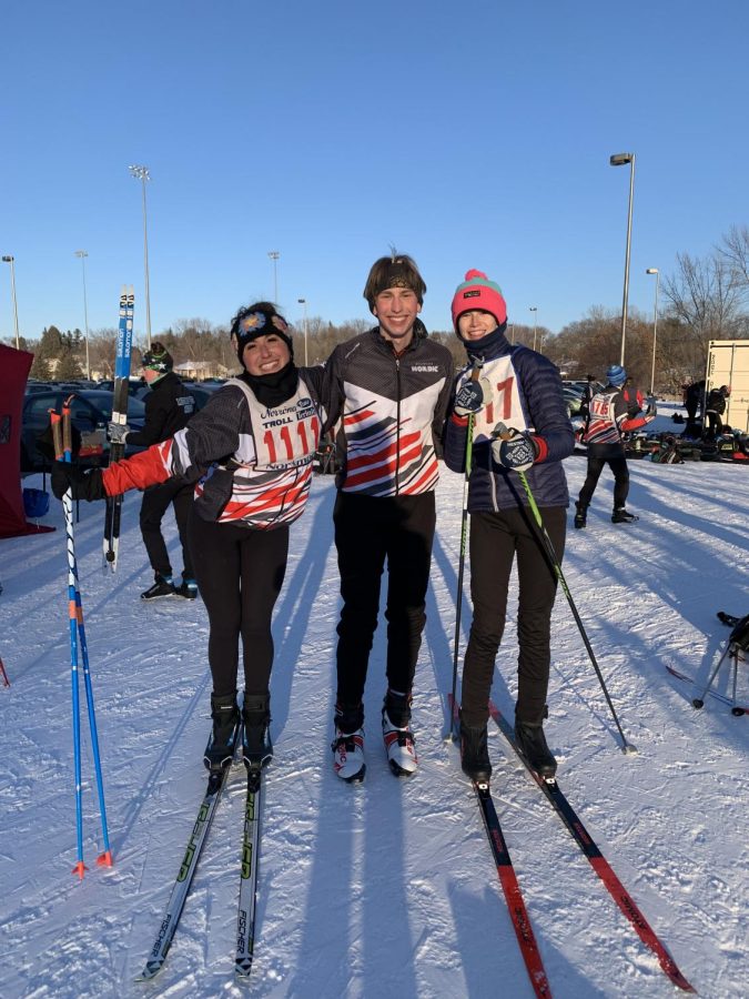 Senior Elly Flaherty on the left and Addie Smitten on the right prepare to start their Nordic ski race, and congratulate Kyle Och in the middle on his race he just finished.