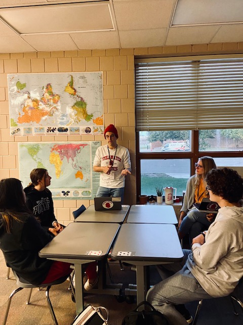 small group of students at a table and two teachers.
