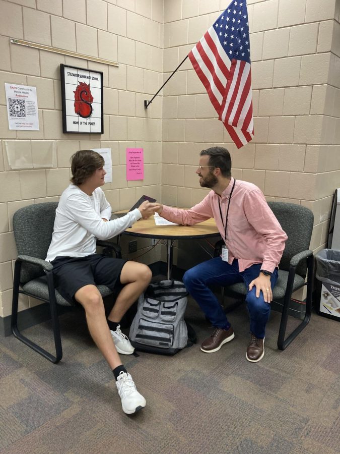 Counselor Alec Shern shaking the hand of a student.