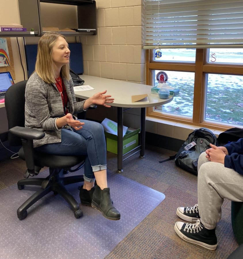 Booher sitting and talking to a student.