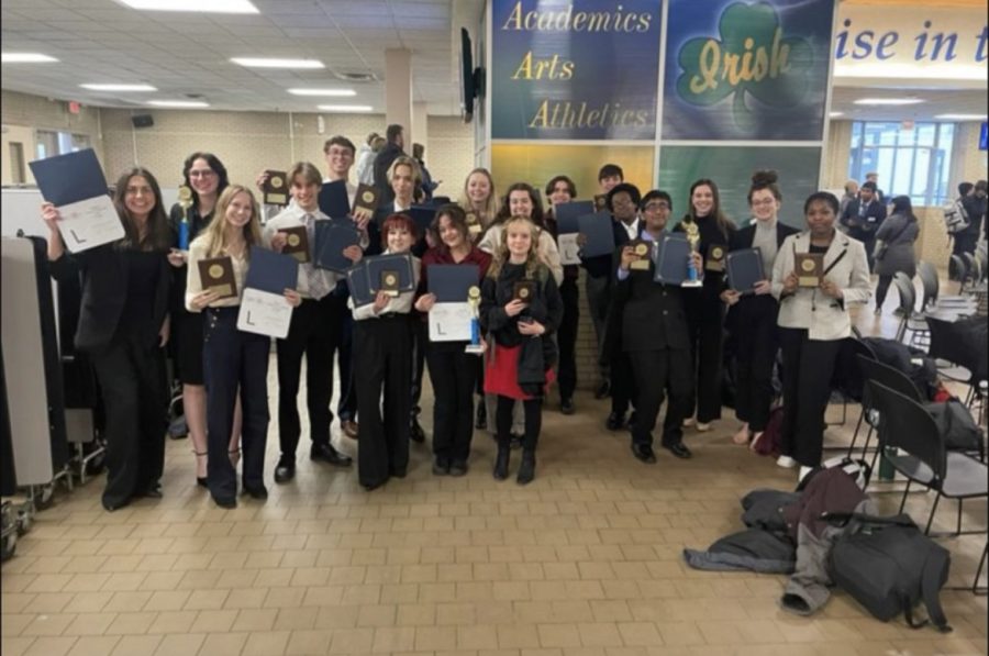 Students in BPA stand together holding all of the awards they received.