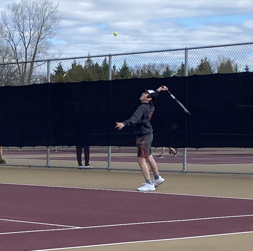 Junior Will Cadenhead serves up a tennis ball during his singles match from the back of the tennis court.