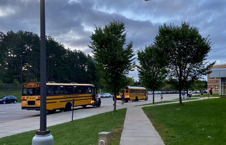 A few buses pull into the bus lot early in the morning. District administration are considering giving high schoolers more time in the morning.