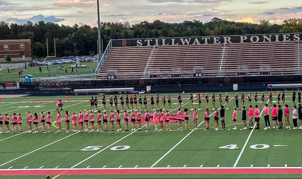 Prior to the Powderpuff game beginning, players and coaches stand in a uniform line for the national anthem. Seniors are wearing pink and juniors are wearing black.
