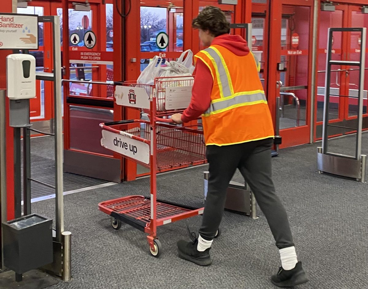 Student Lucas Schlichting works at Target, bringing out a cart of groceries for a customer. He works hard, but he is pushing through for the future.